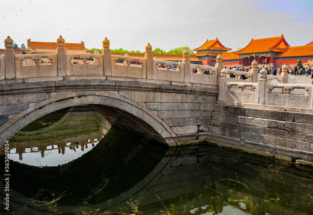 Decorated stone bridge reflected over water in Forbidden City, China. 