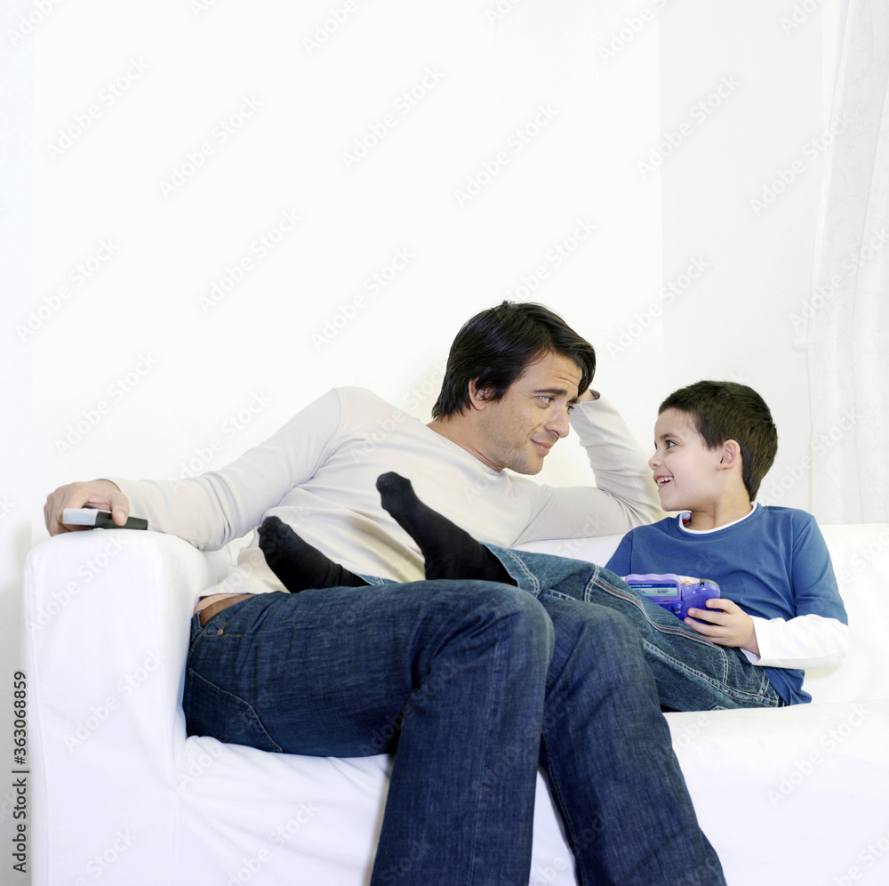 Father and son sitting on the couch chatting Father and son sitting on the couch chatting