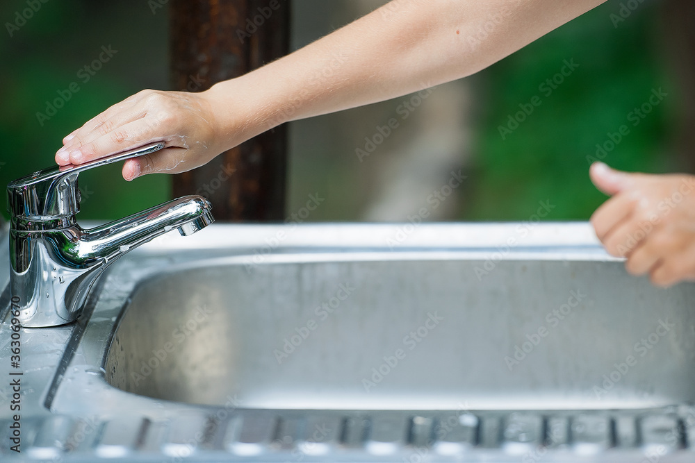 Baby try to turn off water faucet but water still leak. A child's hand