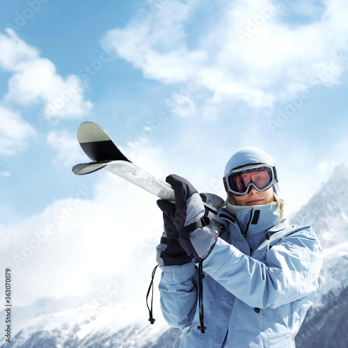 Woman in ski goggles holding snowboard