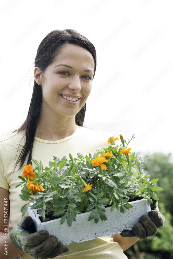 Woman with gardening gloves holding a pot flowers Woman with gardening gloves holding a pot flowers