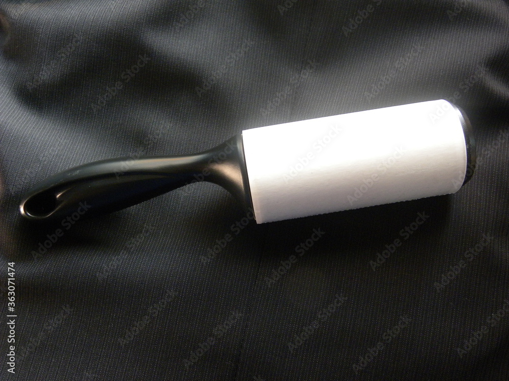 Lint roller kept on black color woolen suit jacket Lint roller kept on black color woolen suit jacket