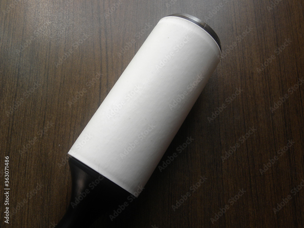 White and black color lint roller kept on wooden table