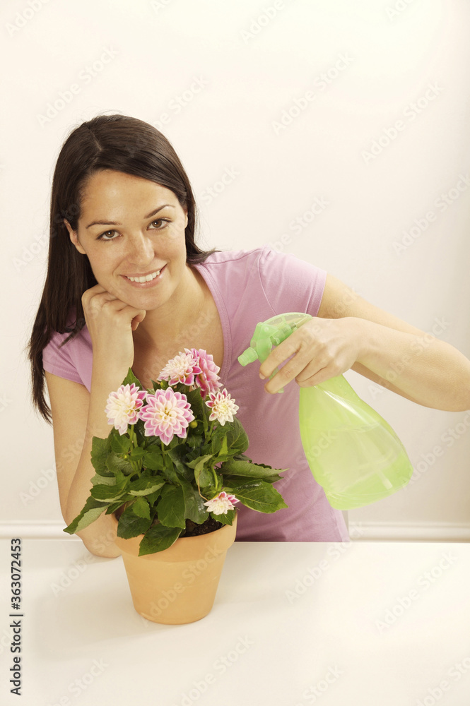 Woman spraying a potted flower