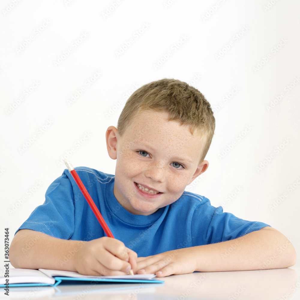 Boy smiling while writing Boy smiling while writing