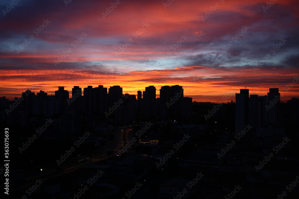 silhueta da cidade de São Paulo com céu colorido em tons de laranja e azul no fim da tarde.