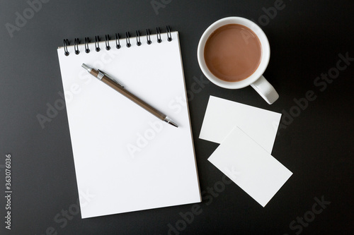 Notebooks   pen   coffee cup and business cards  on black background