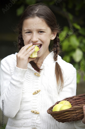 Girl holding a basket of apples while eating an apple