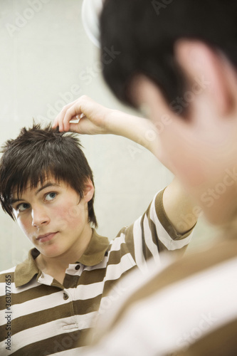 Boy looking at the mirror, styling his hair