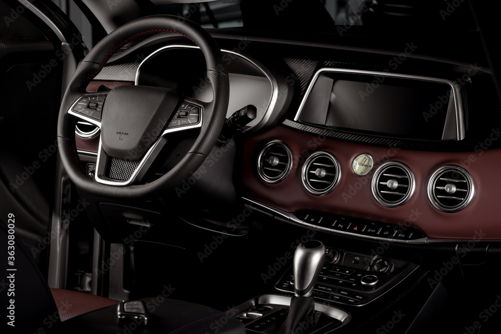 New car interior details with leather steering wheel, automatic transmission and touchscreen center console