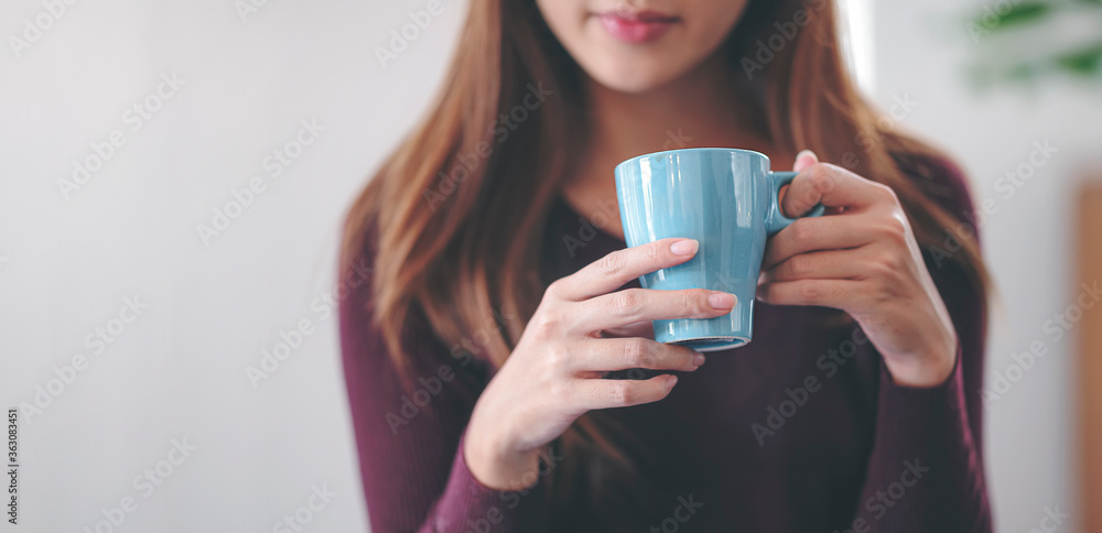 Closeup female hand holding mug of beverage.