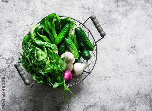 Wallpaper Mural Fresh garden vegetables cucumbers, romaine lettuce, onions, herbs in a metal vintage basket on a gray background, top view Torontodigital.ca