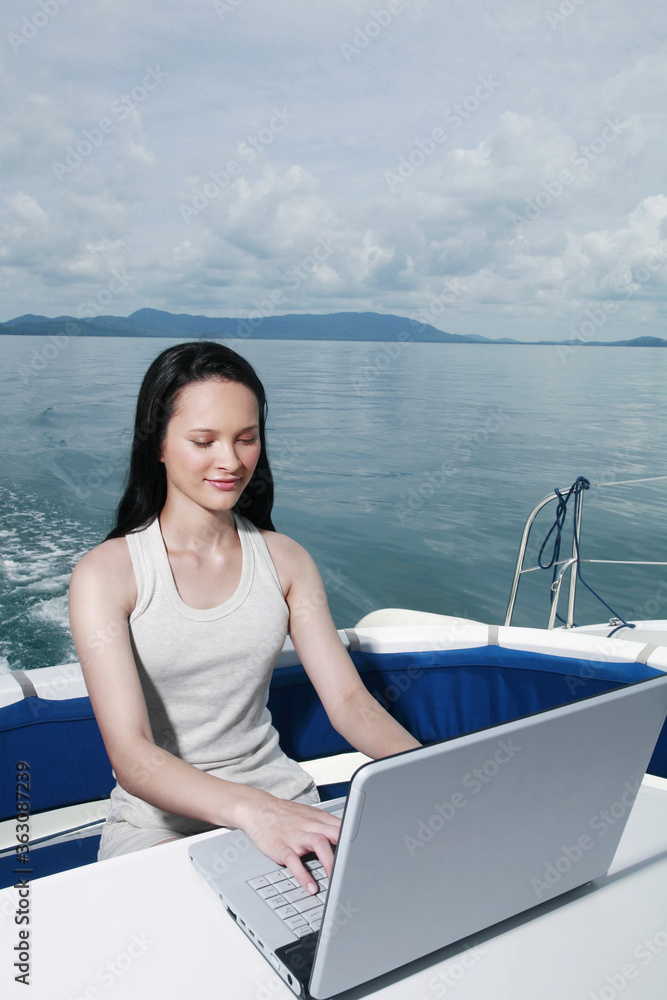 Woman using laptop on yacht
