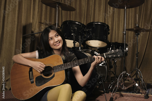 Young woman smiling while playing guitar