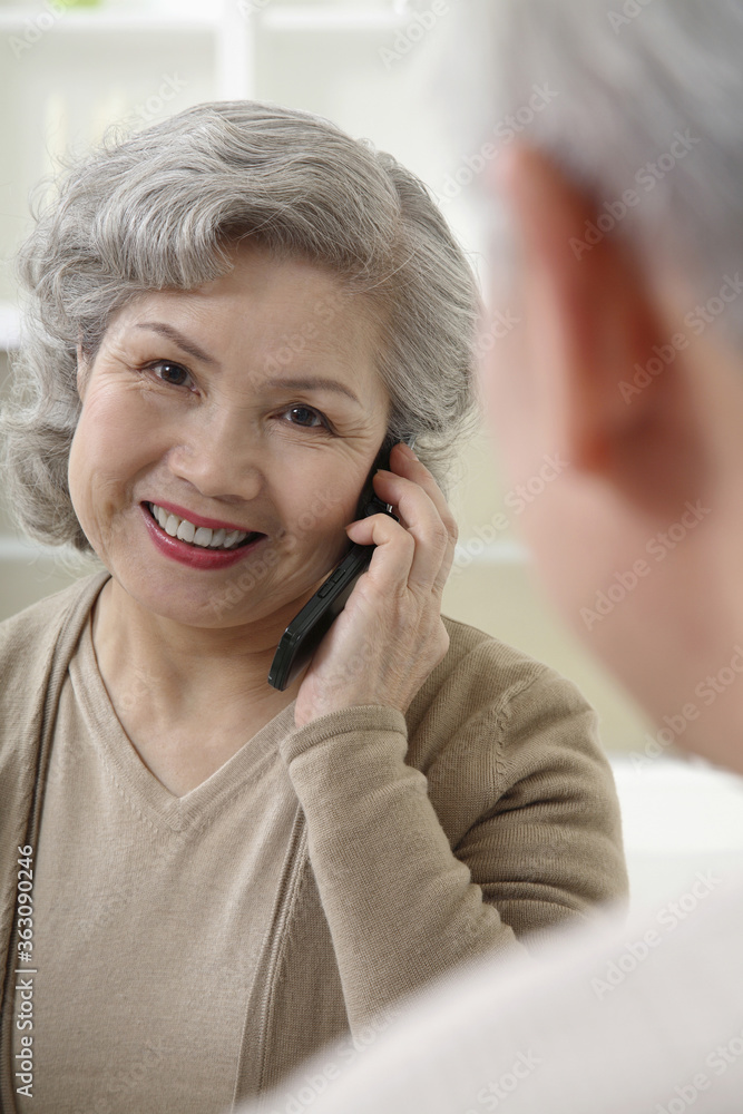 Senior woman talking on the phone, senior man watching Senior woman talking on the phone, senior man watching