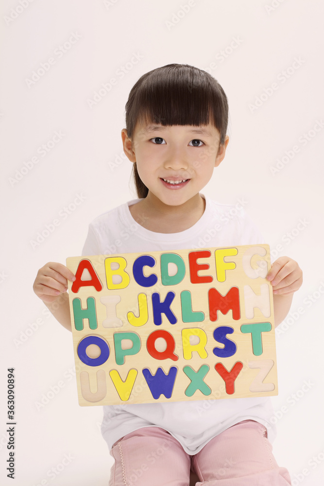 Girl holding up completed alphabet puzzle Girl holding up completed alphabet puzzle