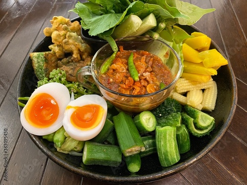 chili shrimp paste with vegetable in black plate on wood table , Thai style