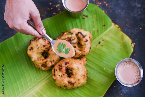 Sambar Vada, Medu Vada, Ulli Vadai South Indian tea time snack. woman serving with hand coconut chutney. milk tea on banana leaf. Dahi Vada, Dahi Bhalla popular breakfast dish Kerala, Tamil Nadu India photo