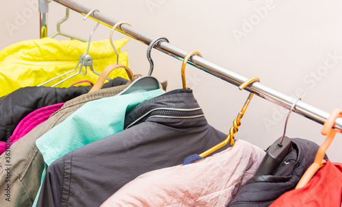 On a hanger in the hallway of the house hangs a collection of multicolored outerwear for cool weather.