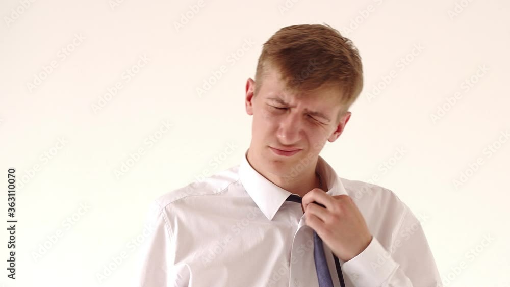 Disheveled worker guy in a white shirt, showing the OK sign, puts on glasses. White background. A young office workaholic is overworked Disheveled worker guy in a white shirt, showing the OK sign, puts on glasses. White background. A young office workaholic is overworked
