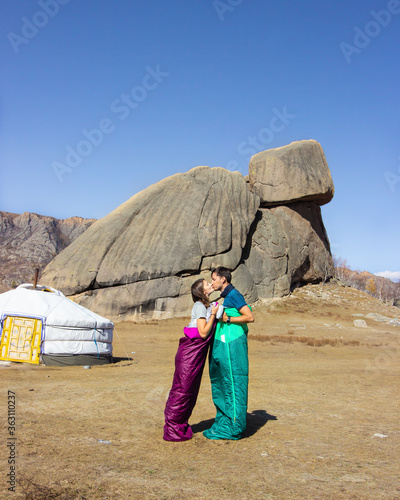 Couple kissing in sleeping bags in front of Turtle rock and ger in Gorkhi Terelj national park, Mongolia photo