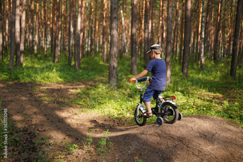 little boy riding on the bike in the forest