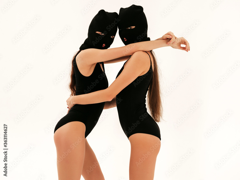 Two beautiful sexy women in black swimwear bathing suit. Models wearing  bandit balaclava mask.Hot girls posing near white wall in studio.Seductive  female in nice lingerie.Crime and violence foto de Stock | Adobe
