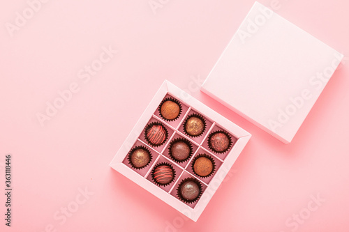 Chocolate truffle candies in a box pink background. Gifts festive food love concept. Horizontal frame copy space