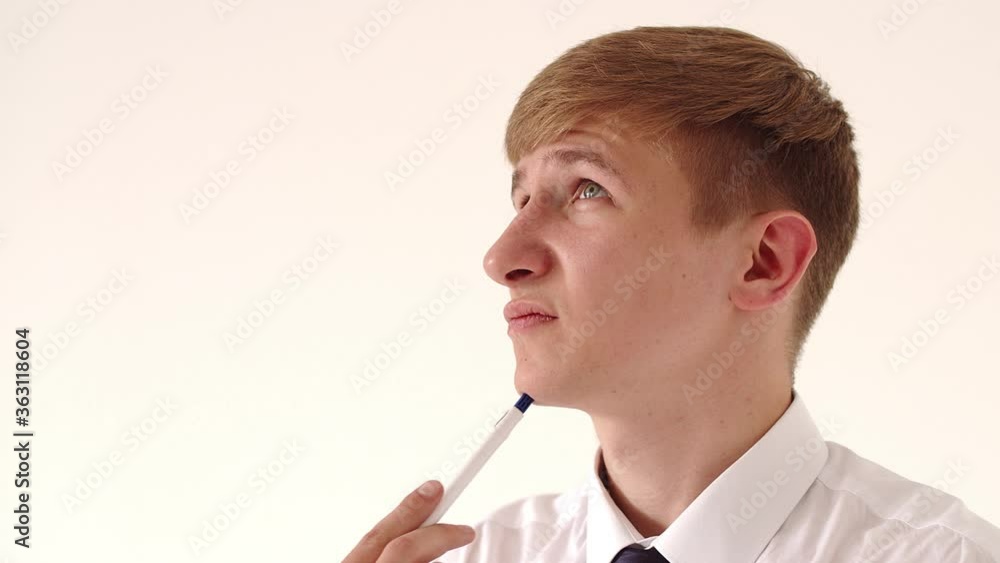 Thoughtful, young, business man holding a fountain pen in his hands thinks over ideas, develops a business strategy, looks into the distance, a pensive worker takes a break, dreams or visualizes in
