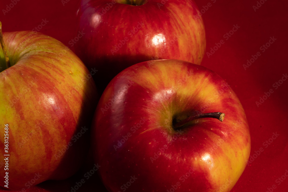 close up of many delicious shiny apple on a red studio background close up of many delicious shiny apple on a red studio background