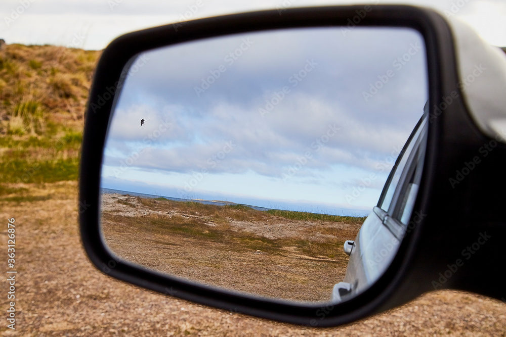 Car Mirror and reflection of tundra and sky in it.