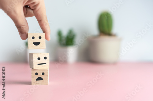 Smile face and cart icon on wood cube. Optimistic person or people feeling inside and service rating when shopping, satisfaction concept. photo