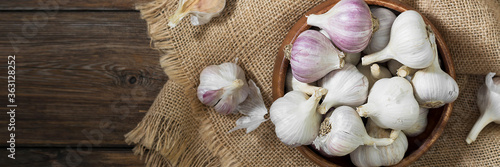 Garlic in a wooden bowl on a wooden table. lots of garlic in a bowl. Garlic close-up. Banner with space for text photo