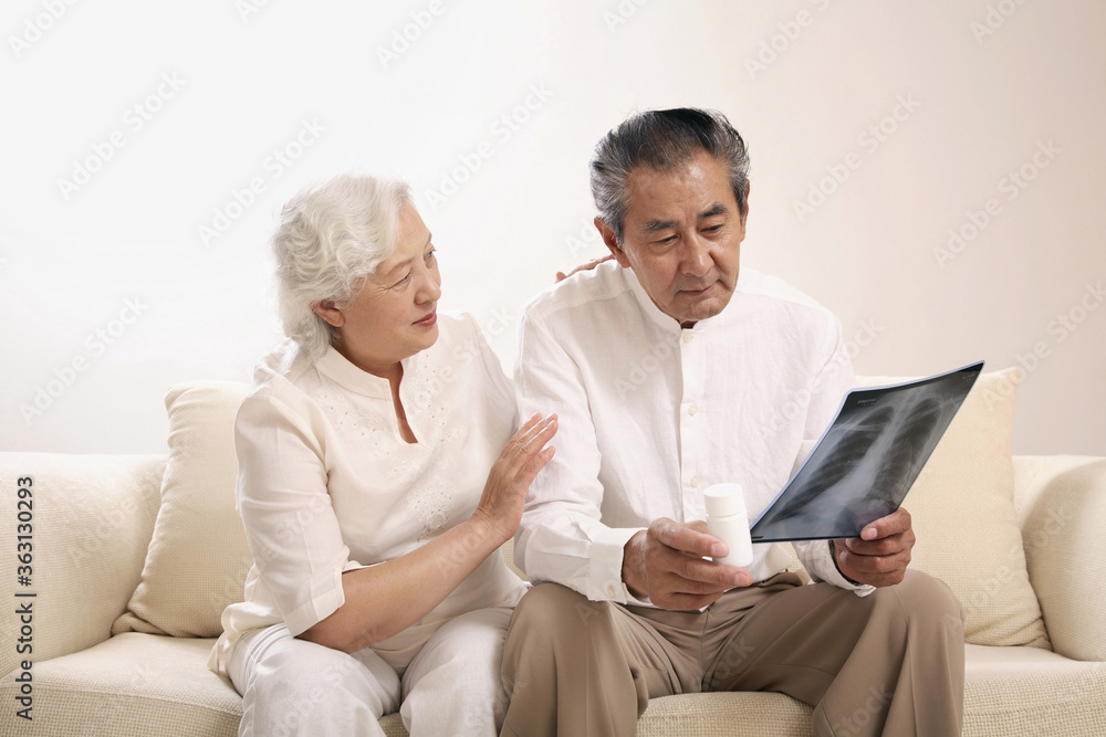 Senior man with a bottle of pills looking at his x-ray sadly, senior woman consoling him Senior man with a bottle of pills looking at his x-ray sadly, senior woman consoling him
