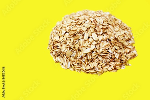 Oatmeal flakes circle isolated on a yellow background, with place for an inscription. Bunting circle symbol. Healthy eating A pile of oatmeal shaped shot from above.