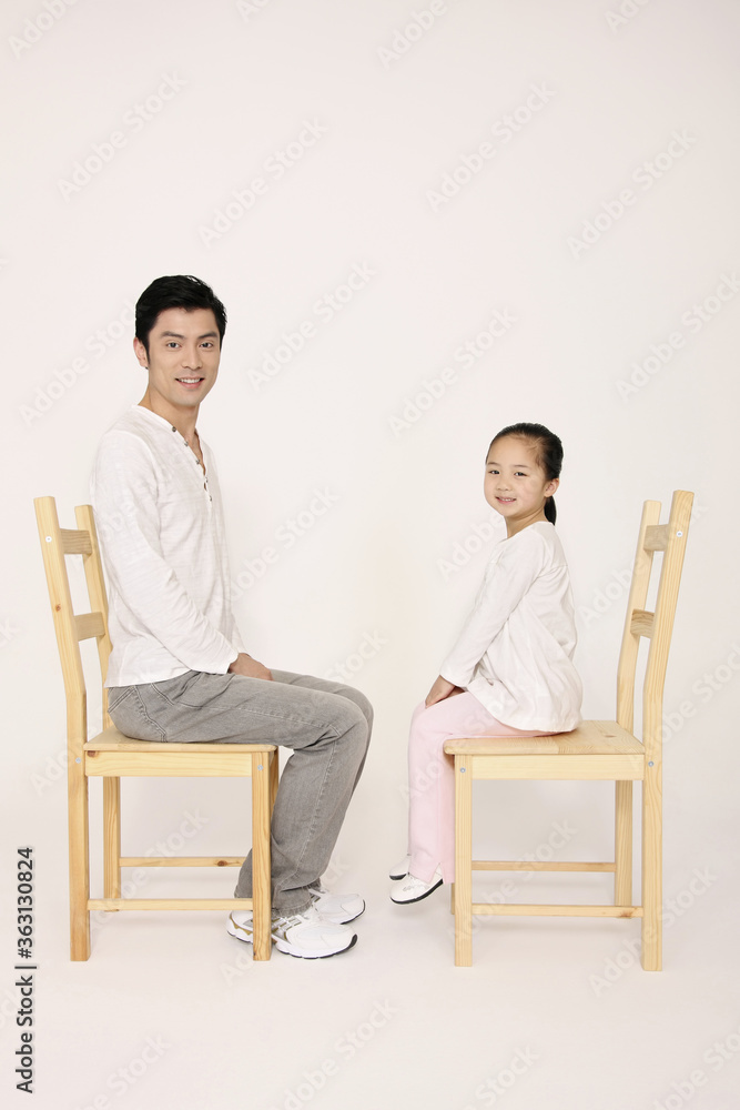 Obraz premium Man and girl sitting on wooden chairs