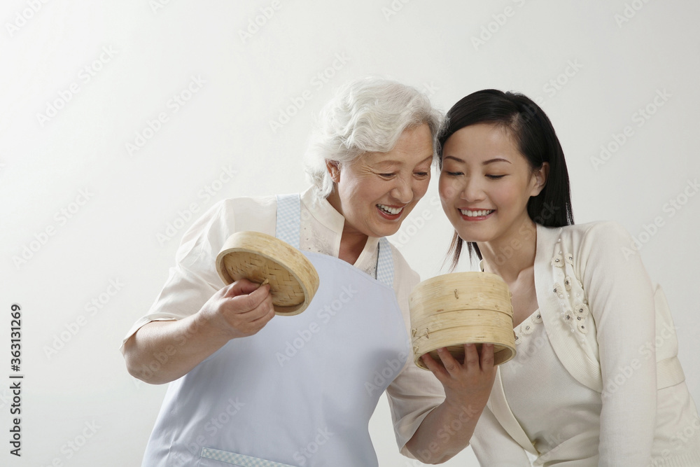 Senior woman and woman smiling while looking at dim sum in the bamboo steamers Senior woman and woman smiling while looking at dim sum in the bamboo steamers