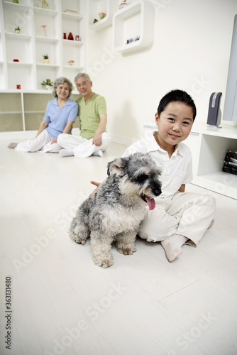 Boy posing with dog, senior man and senior woman watching