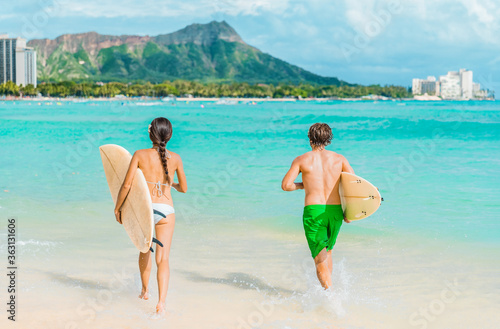 Photography Hawaii Honolulu couple surfers going surfing on waikiki beach with surfboards running in water