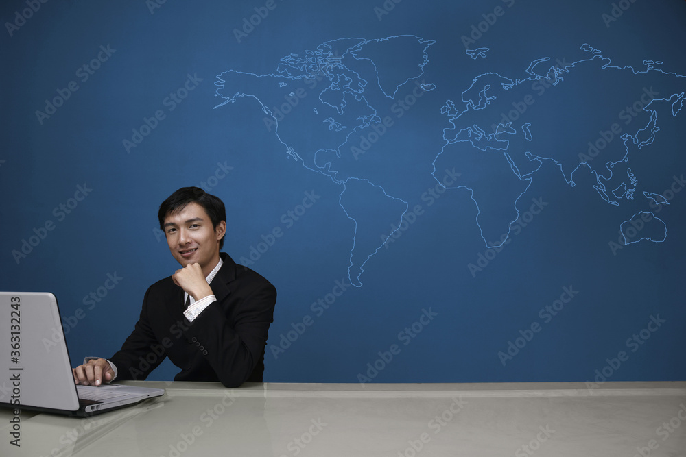 Businessman smiling at the camera while using laptop Businessman smiling at the camera while using laptop