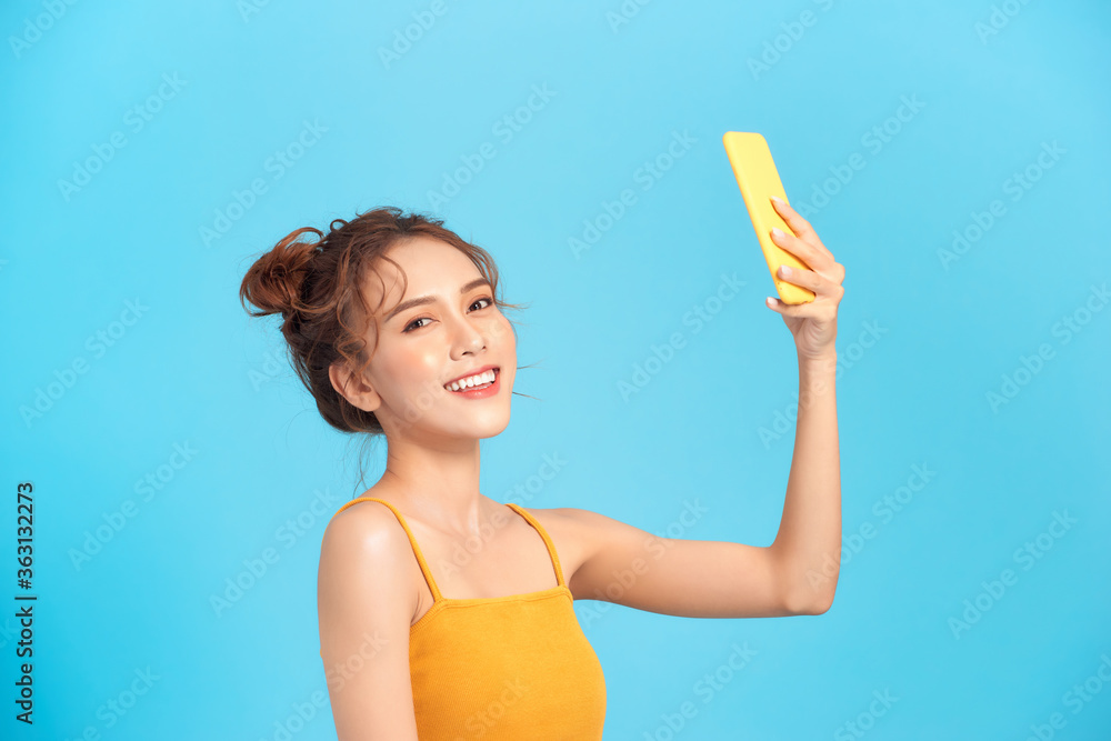 Summer, fun, technology and people concept - cool girl makes self-portrait on the smartphone on blue Summer, fun, technology and people concept - cool girl makes self-portrait on the smartphone on blue