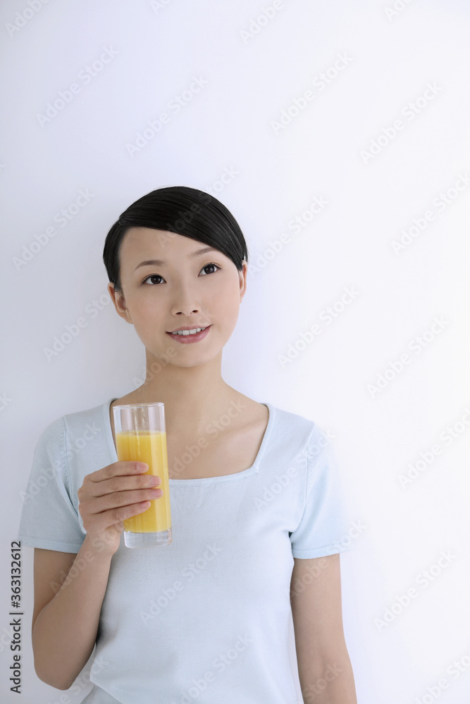 Woman contemplating while holding a glass of orange juice Woman contemplating while holding a glass of orange juice