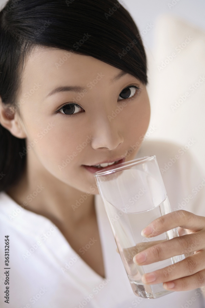 Woman smiling while drinking a glass of water Woman smiling while drinking a glass of water