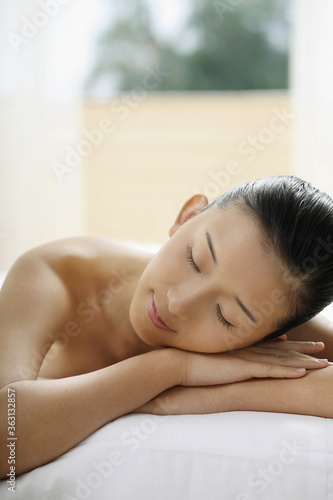 Woman lying forward on massage table with her eyes closed © ImageHit