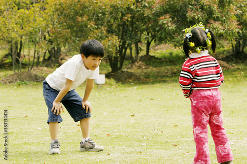 A tired boy standing in the park with his sister