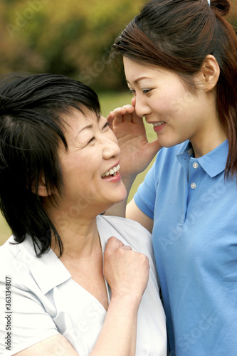A lady whispering a joke into her mother's ear