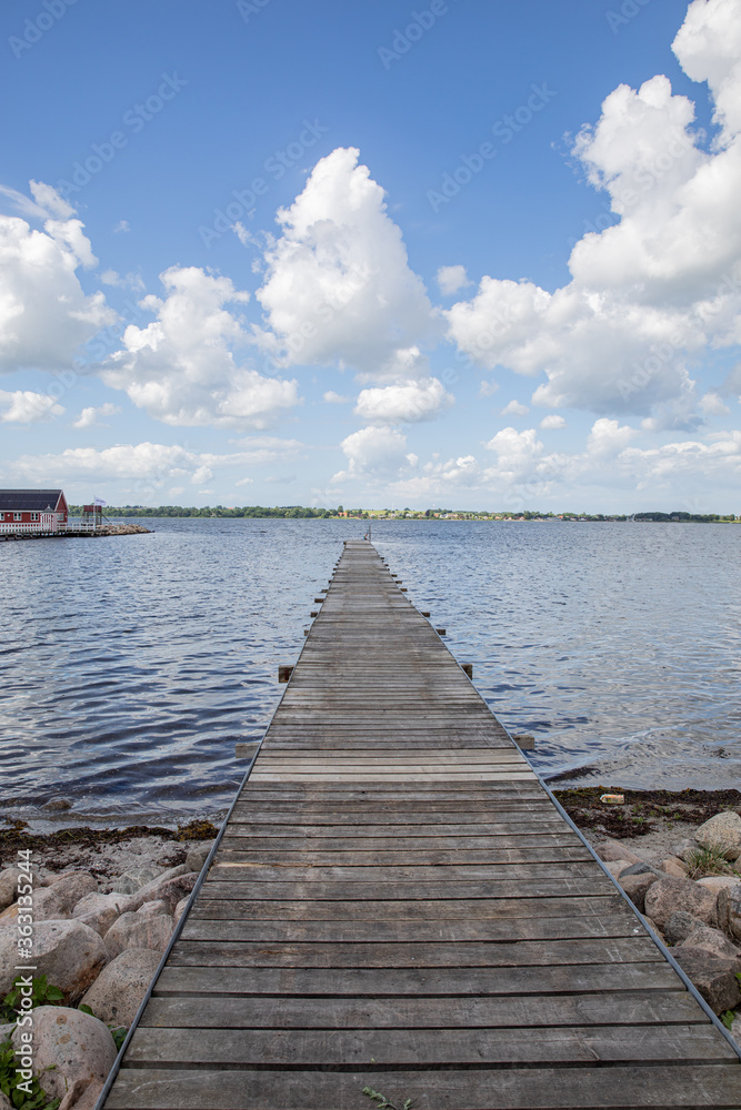 old bridge going out into the water with blue sky and clouds 