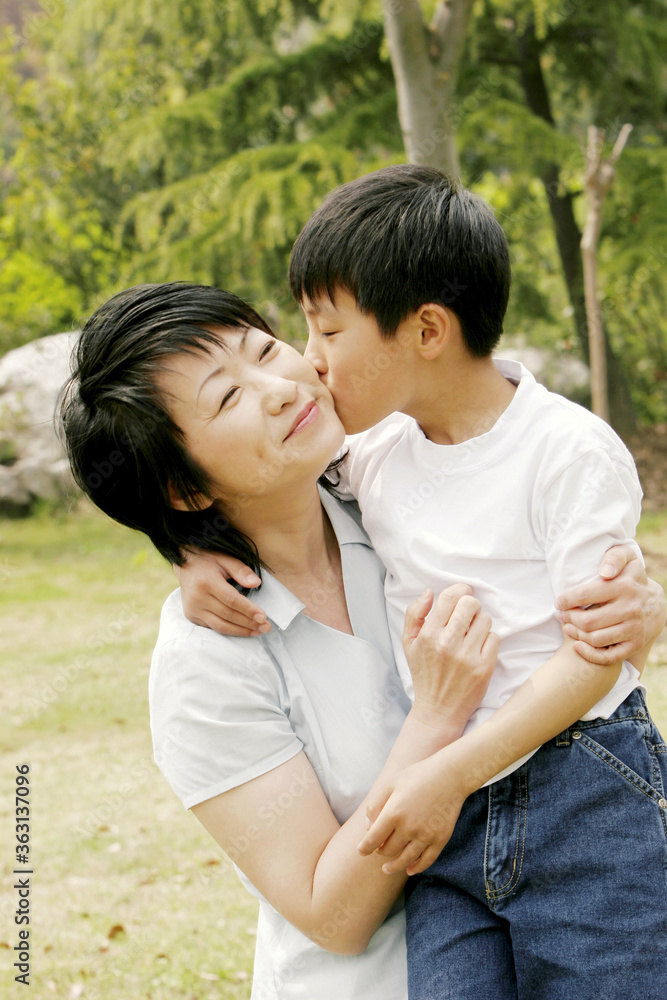 A boy giving her mother who is holding him in her arms a peck on the cheek A boy giving her mother who is holding him in her arms a peck on the cheek