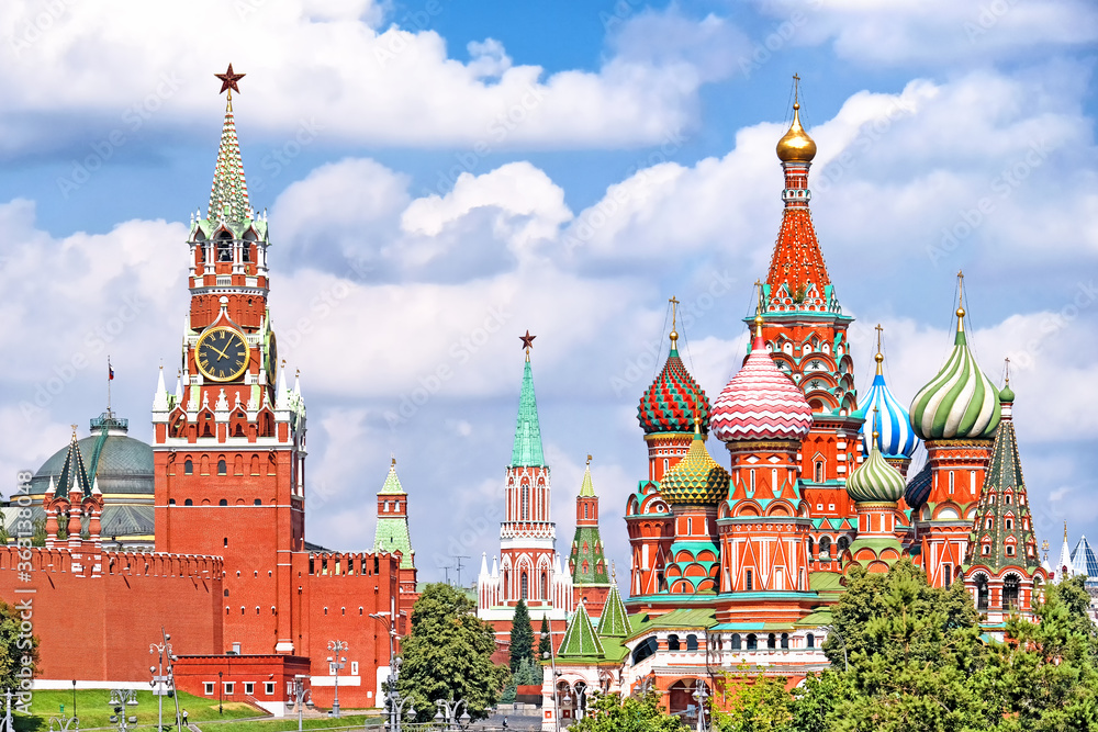 famous moscow city russia kremlin landmark spasskaya clock tower and saint basil's cathedral on red square on summer against blue sky with clouds background. Street view of russian historic heritage famous moscow city russia kremlin landmark spasskaya clock tower and saint basil's cathedral on red square on summer against blue sky with clouds background. Street view of russian historic heritage