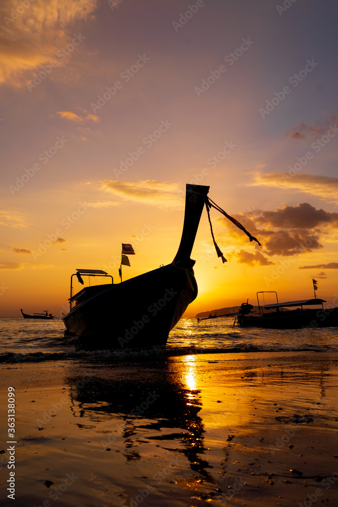 Traditional long-tail boat on the beach in Thailand at sunset
